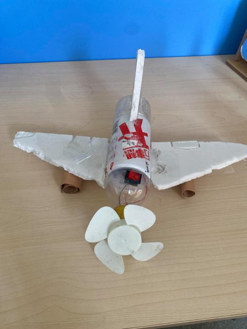 小学课桌上折了翅膀的手工航模和散落的水彩笔