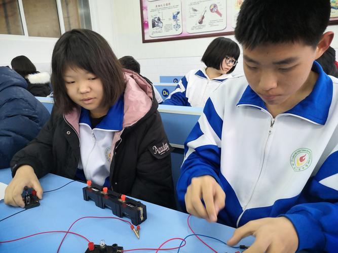 初中物理课上老师蹲在实验台边和学生一起检查电路接线