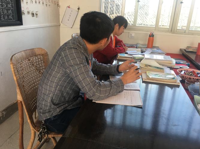 初中教师办公室两位班主任对着成绩表争执的实拍图