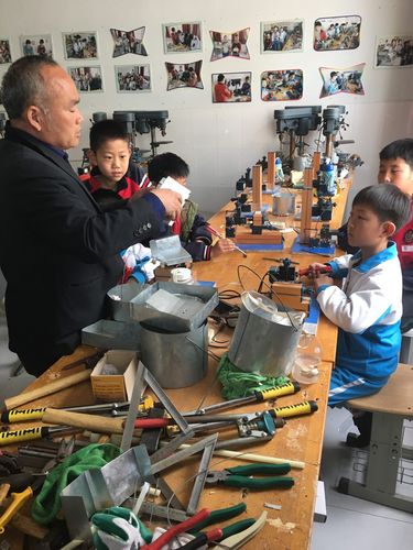 工业工程师在乡村小学教孩子们使用工具实景