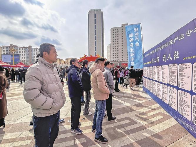 毕业生在招聘会看信息墙，焦虑地翻阅手机