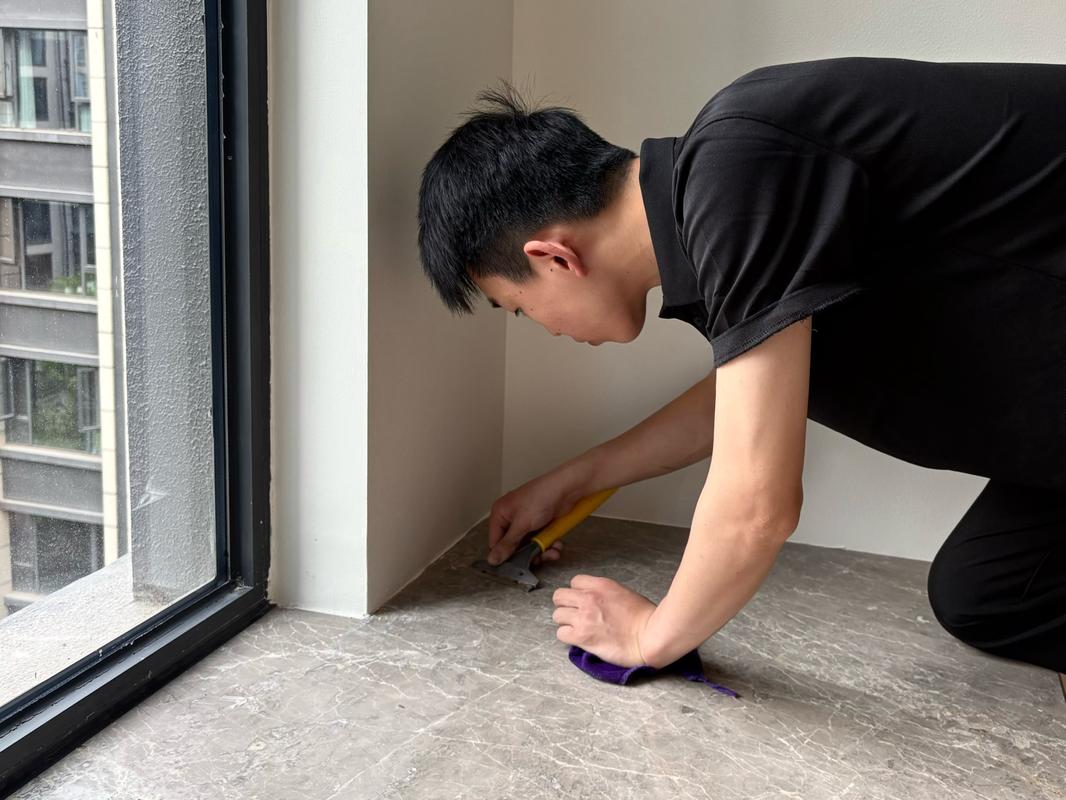 双手使用长柄除尘掸清洁白墙