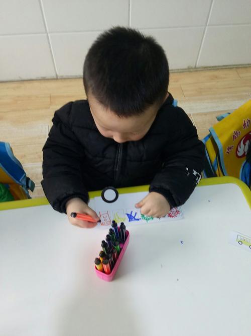 18个月宝宝抓粗杆蜡笔在快递盒上画线条的手部特写