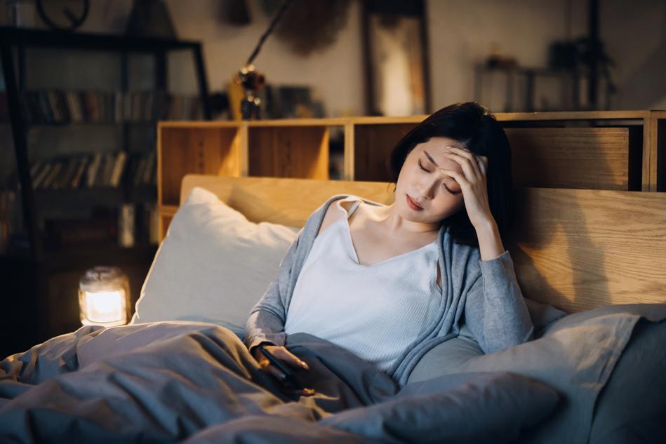 卧室里坐在床边扶额头掉发的妈妈场景图