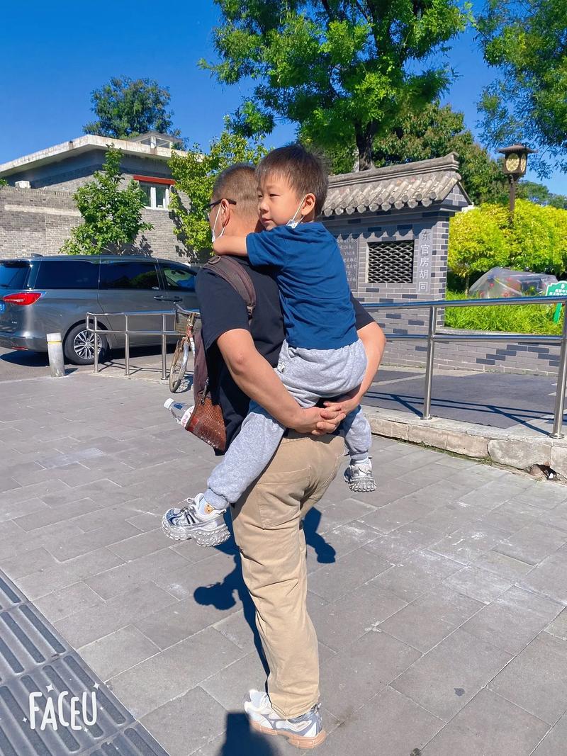 父亲抱着在游乐场哭泣的幼儿轻拍后背安慰