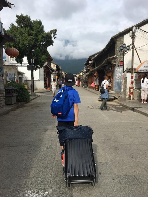 丽江古城北门石板路游客拖行李箱场景