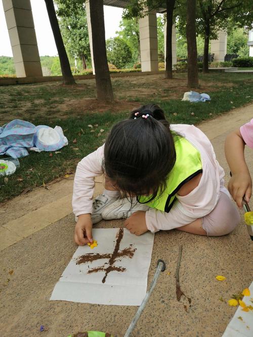 孩子用树枝在小区泥地上写涂鸦的实拍