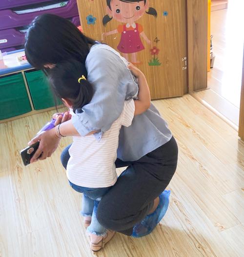 托班门口妈妈蹲下来和1岁多宝宝击掌道别实拍图
