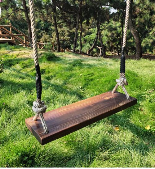 乡村老槐树上粗麻绳拴着的简易木板秋千