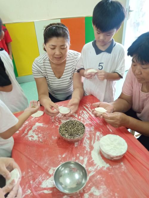 小朋友蹲在奶奶身边学包中秋月饼的家庭场景照