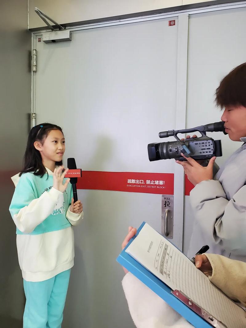 一群小学生围坐在校门口,采访门卫爷爷,笔记本上写满字