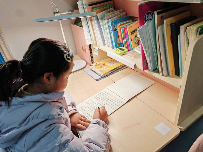 夜晚台灯下孩子独自专注写作业的温馨场面