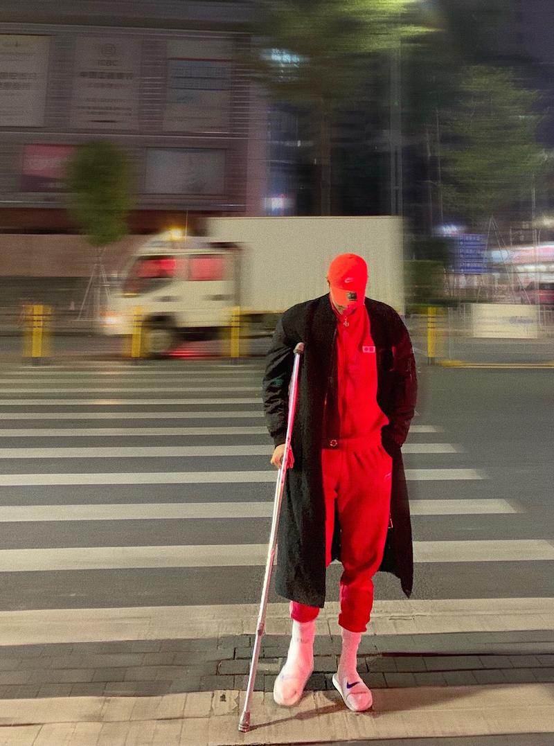 城市街头年轻人拄着木质手杖协调搭配