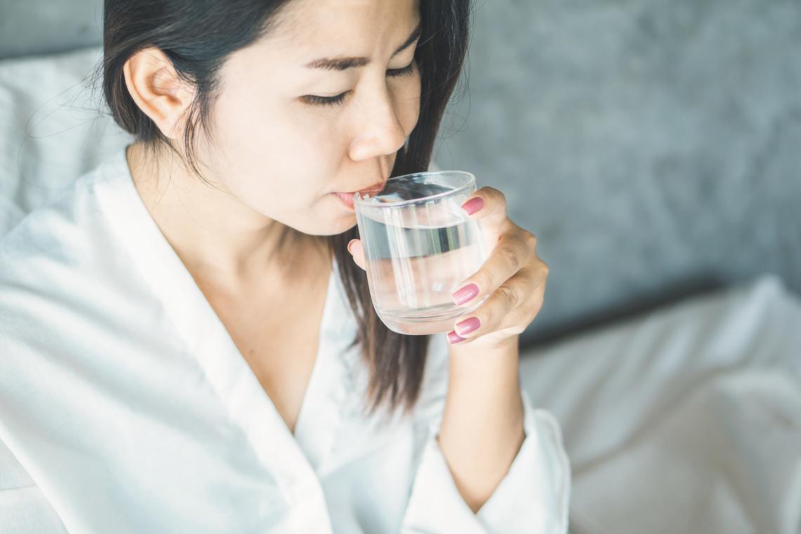清晨睡眼惺忪的女人在水杯前犹豫