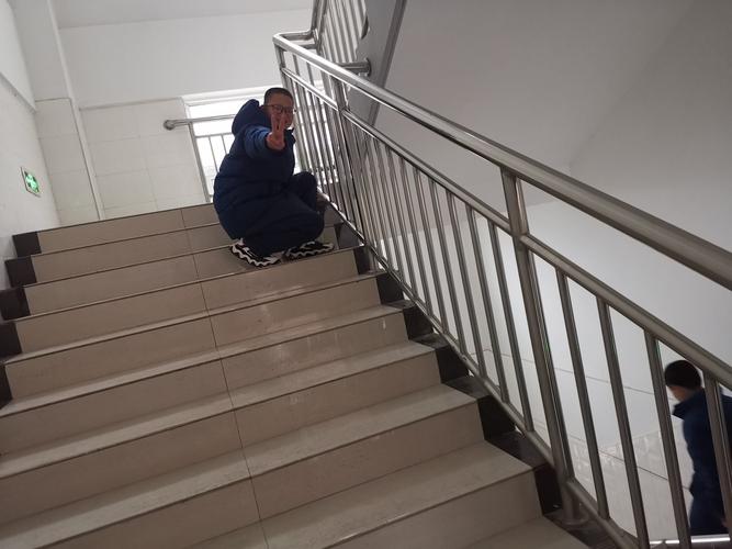 高中生蹲在教学楼走廊扶墙喘气的侧影