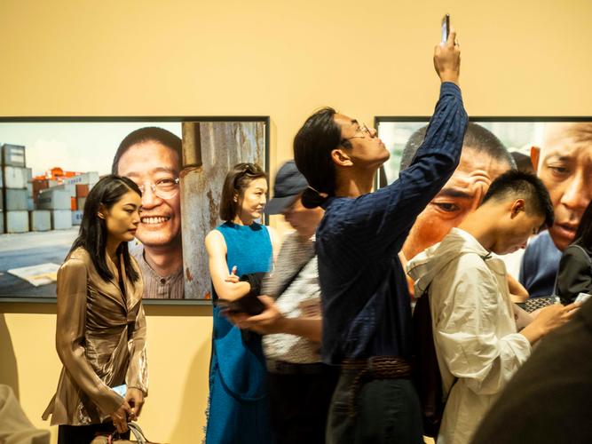 观众在当代摄影作品展览前举手机拍摄展品