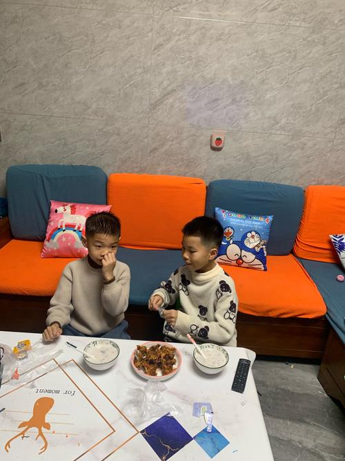 客厅两个兄弟并排坐一起打游戏分享零食