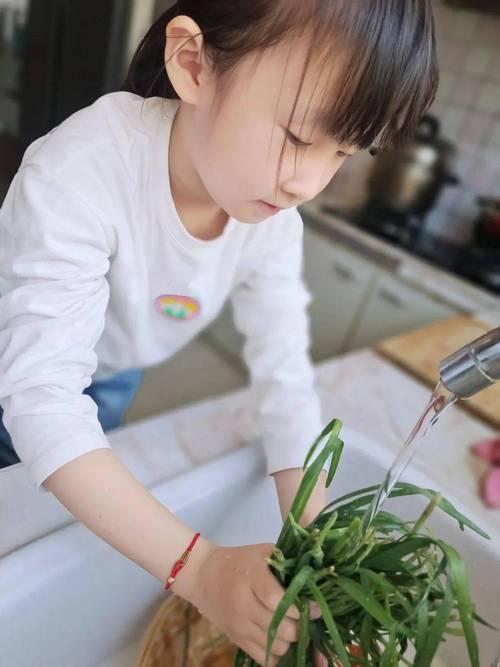 两岁宝宝在厨房帮妈妈摘青菜场景图