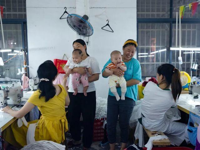 工业流水线旁的全职妈妈一手操作设备一手拿婴儿监控画面