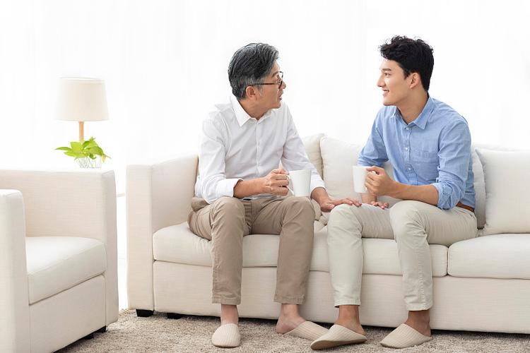 青春期孩子和工人父亲坐沙发谈心场景