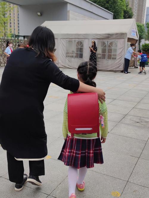 小学放学门口 妈妈接三年级儿子 孩子攥着半块橘子糖抿嘴