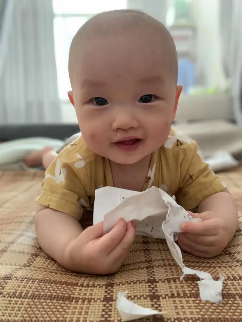 一岁宝宝啃着硬纸板触摸书边大笑实拍近景
