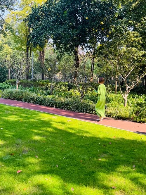 中年女性小区楼下绿植旁散步放松场景