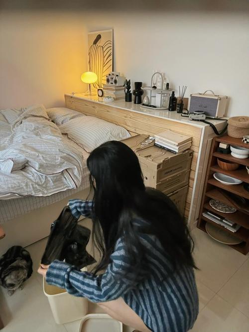 一个人坐在卧室地板上,对着一件旧毛衣拍照,旁边有纸箱