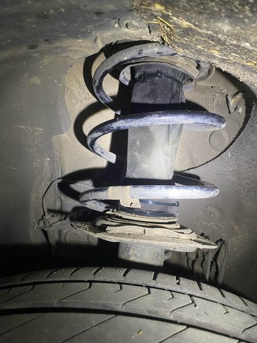 汽修师傅用平口螺丝刀扒开减震器防尘套检查内部渗油状态