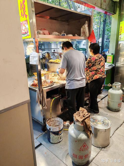 老小区巷口早餐店门口塑料凳上放着手机和酱肉包