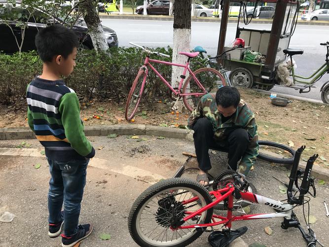 傍晚小区单元门口父子蹲地拆旧自行车轮胎