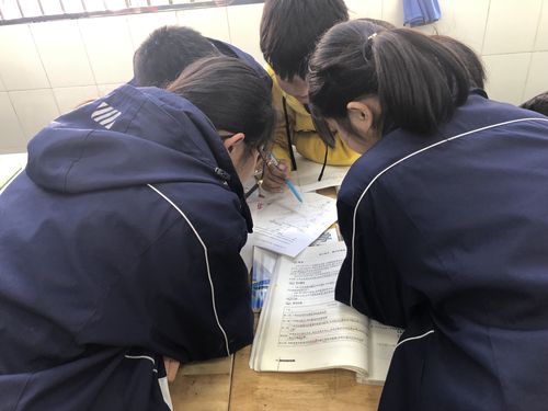 初三学生课间趴在走廊栏杆上跟同伴讨论数学解题思路的实拍
