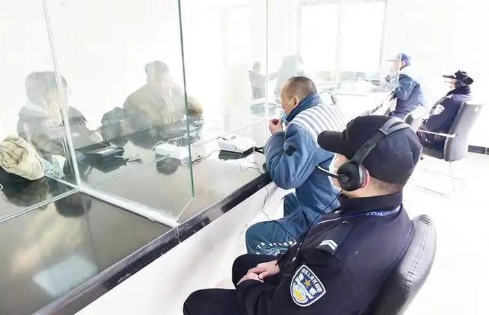 律师在会见室隔着玻璃与嫌疑人通话