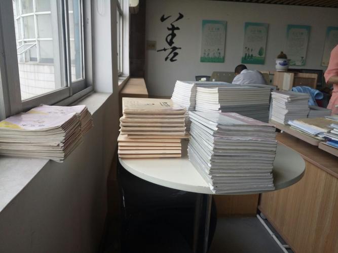 初中办公室窗台上按摞摆放的不同难度学生作业本