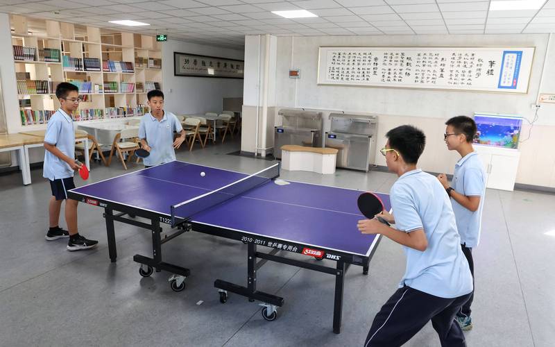 小学课后服务时间走廊上学生打乒乓球的实景