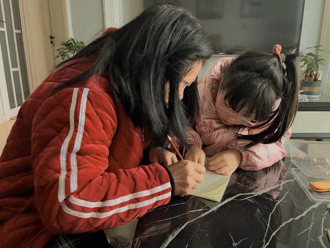 宝妈趴在书桌前对着保险合同条款仔细核对的场景