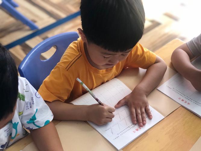 幼儿园中班孩子坐椅子上歪歪扭扭写字的真实场景
