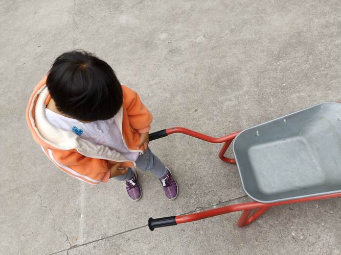 小孩拉着缠了橡皮筋轮子的拉杆箱在小区步道走