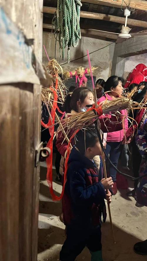 池州茅坦村老人在樟树下扎制平安草龙灯的稻草堆