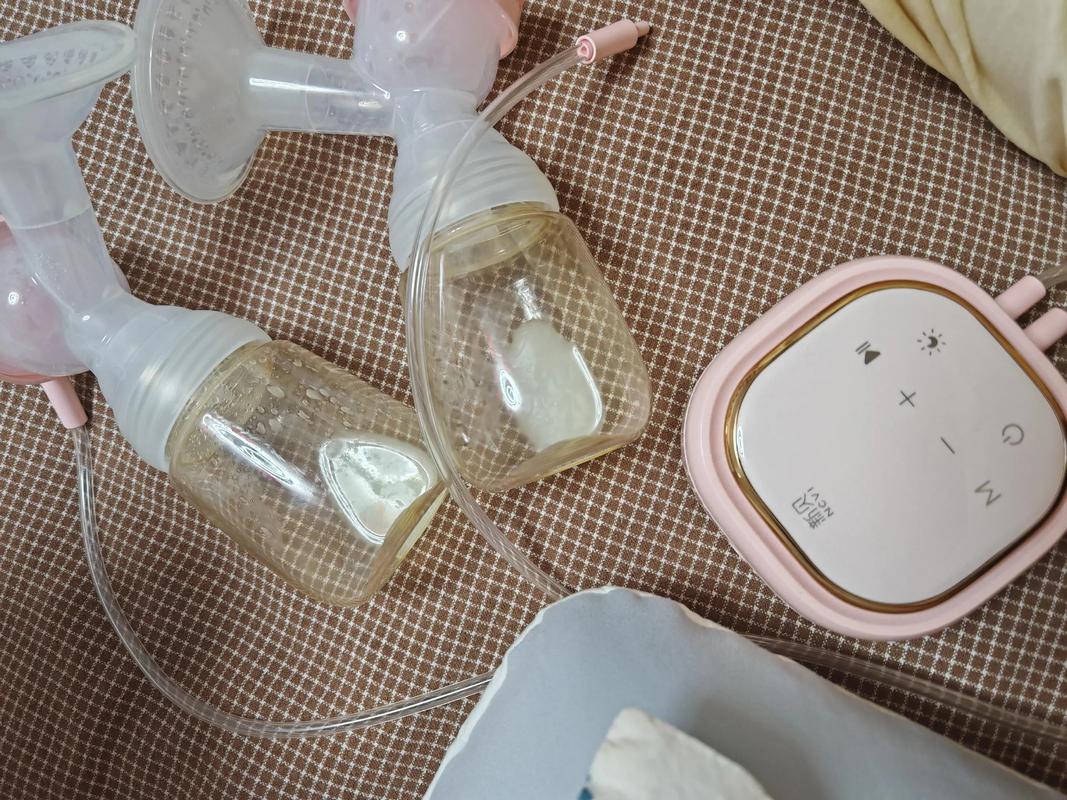 妈妈抱着婴儿自拍，背景是吸奶器和储奶袋