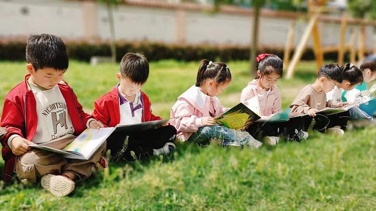 放学后的孩子在公园草地看书