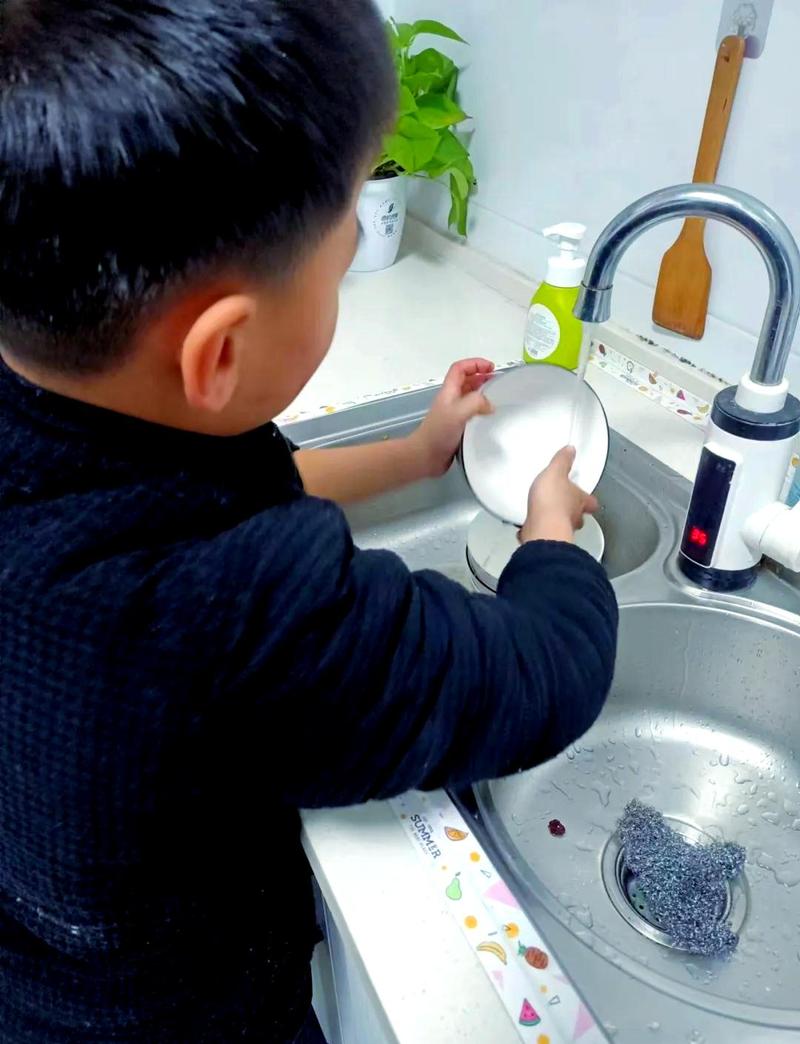 孩子踩着小板凳在水槽边洗碗的温馨场景