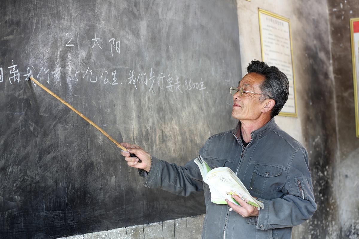 乡村教室讲台上堆着不同版本的旧课本