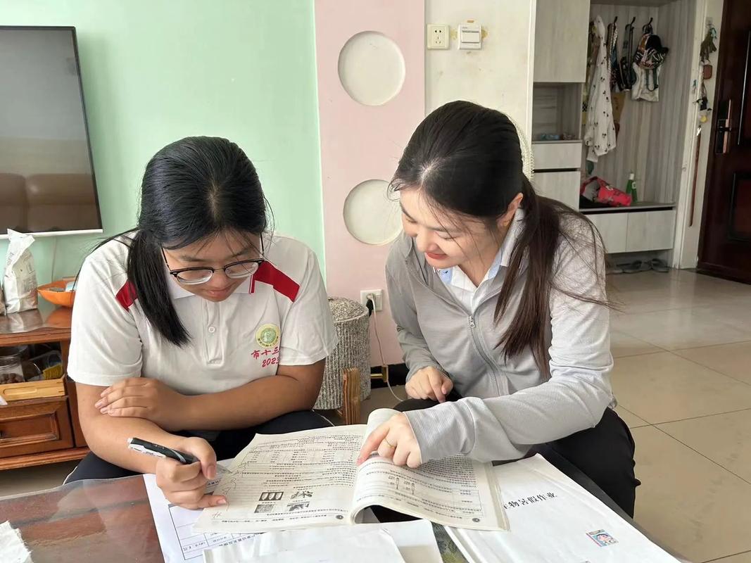 家访时老师与学生在堆满书籍的旧书桌旁交谈