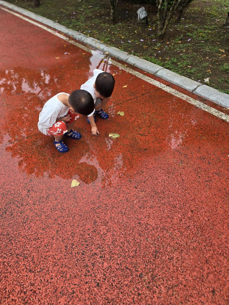 亲子在雨后水泥地上踩水坑欢笑的场景