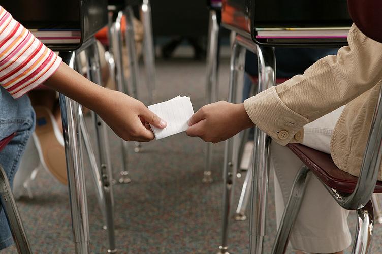 中学教室课桌上递小纸条的女生