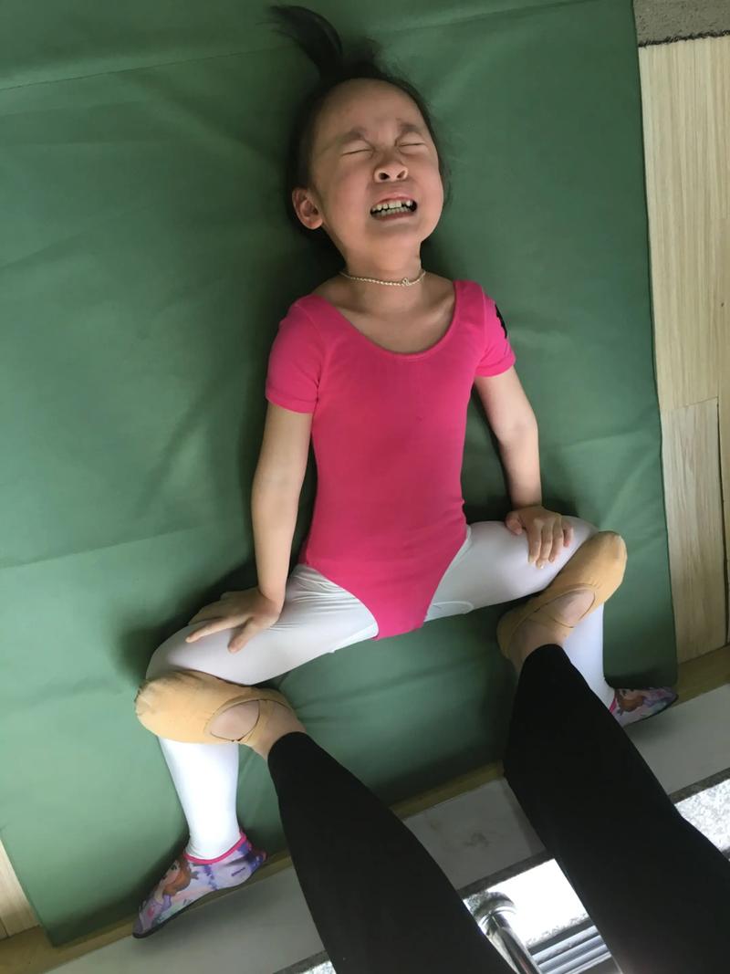 杂技小演员压腿拉韧带痛苦表情特写