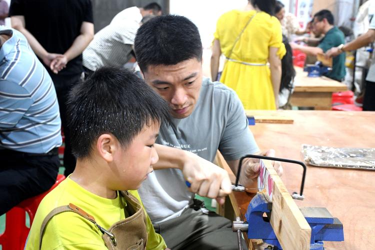 亲子木工工作坊现场父亲与孩子共同锯木头