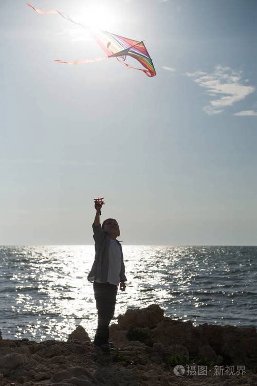 海边沙滩孩子放飞风筝剪影