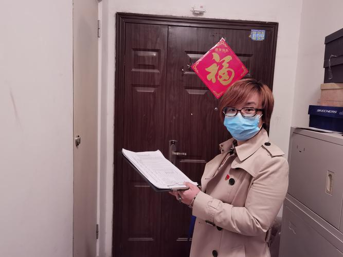 老小区单元楼门口教师拎着纸质文件袋站着